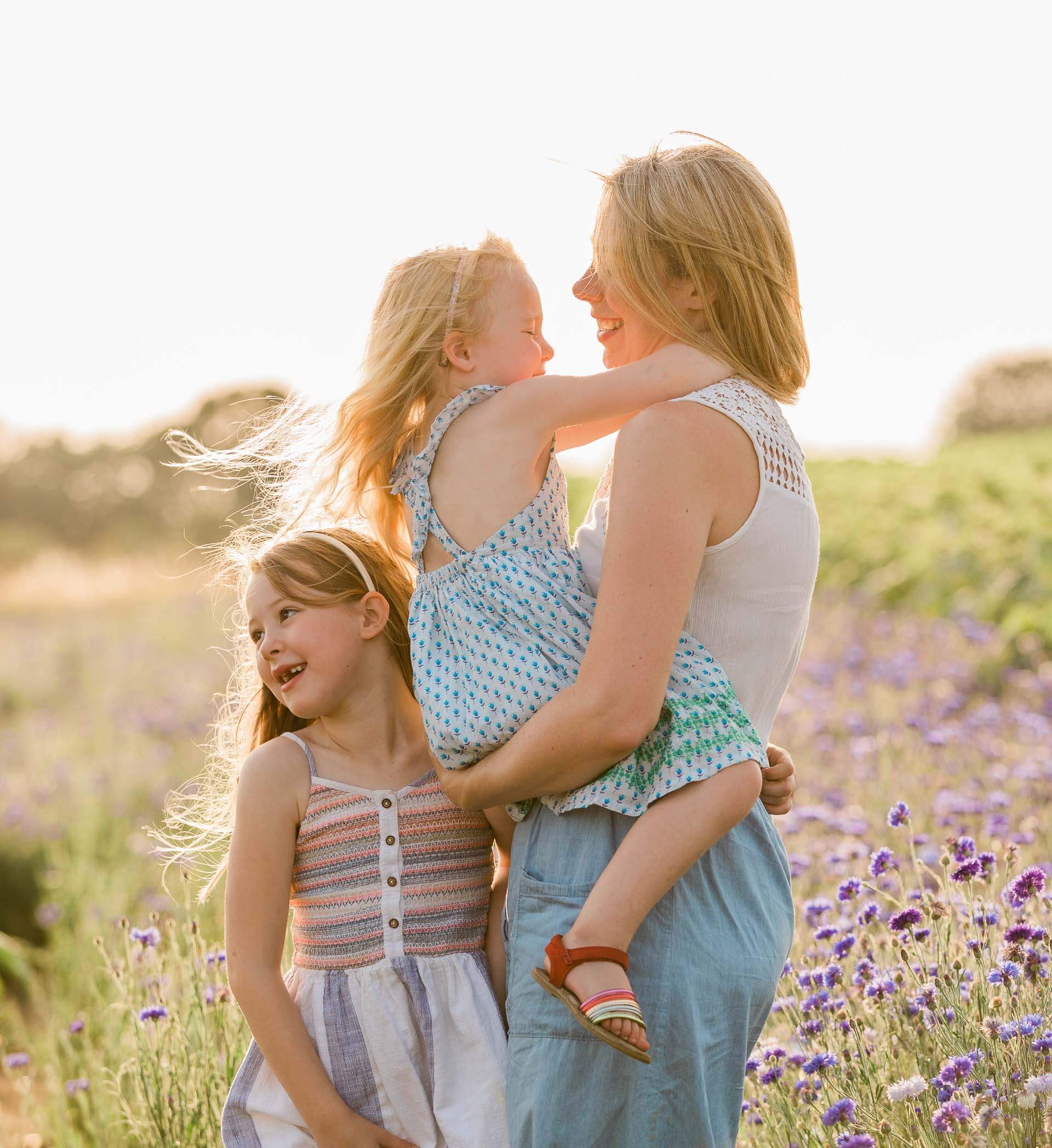 Mother with her gorgeous daughters, back lit with the wind in their hair photographed by Chelmsford photographer Kika Mitchell Photography