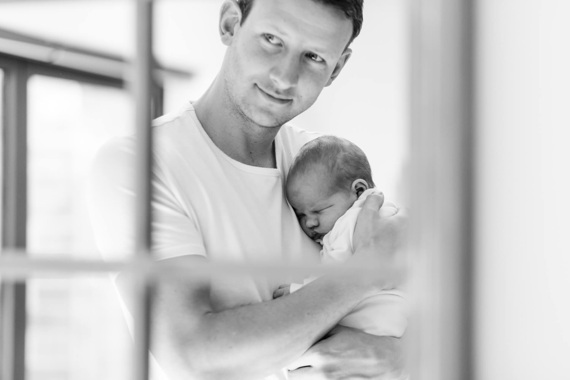 Black and white image of Father and son in mirror reflection captured by Chelmsford Newborn photographer Kika Mitchell Photography