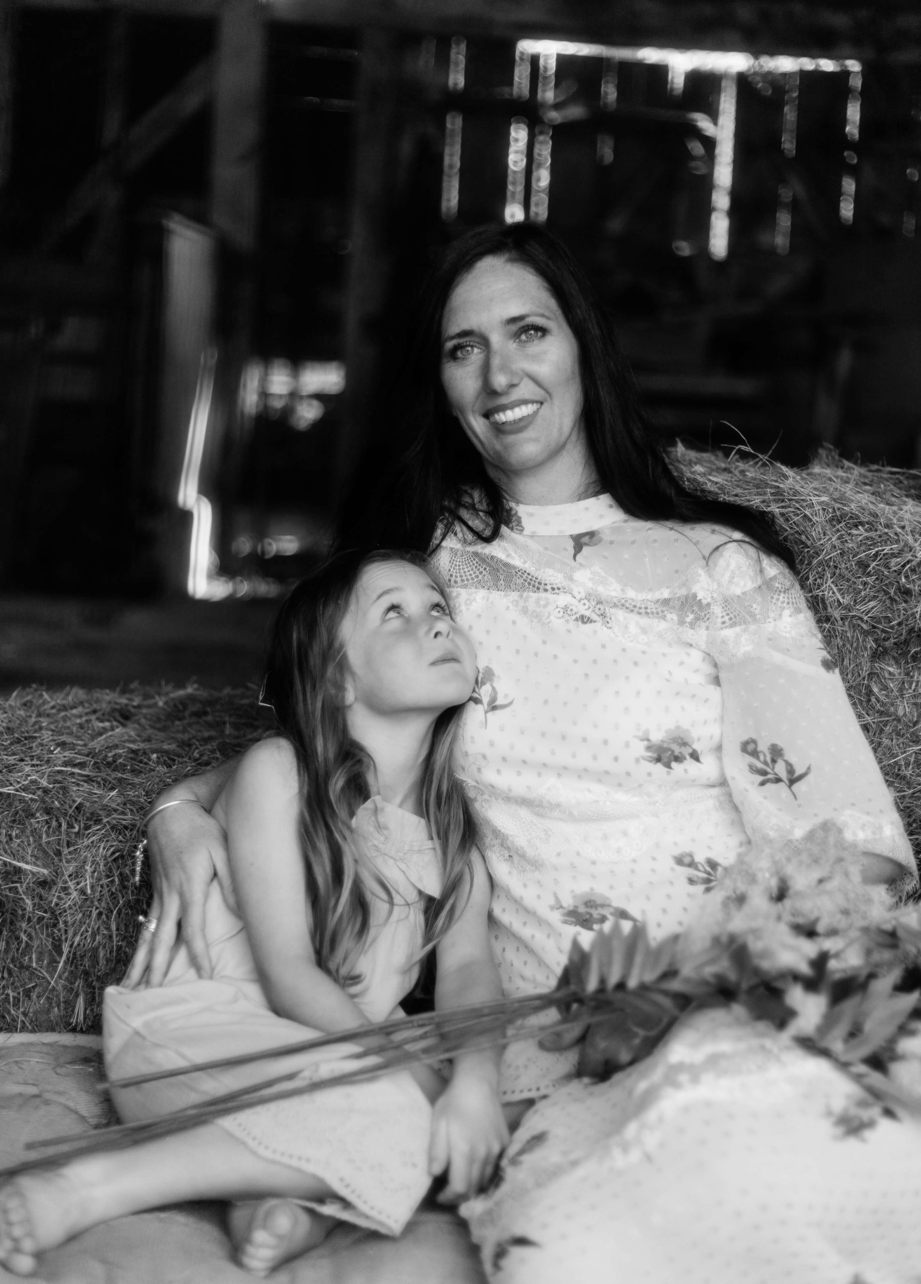 monochrome portrait of mother and youngest daughter holding flowers looking up by Chelmsford photographer kika mitchell photography