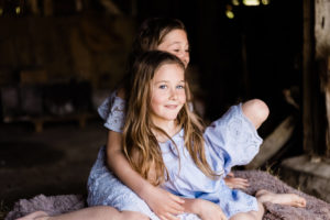 2 sisters in blue sat on hay bale captured by Chelmsford Kika Mitchell photography