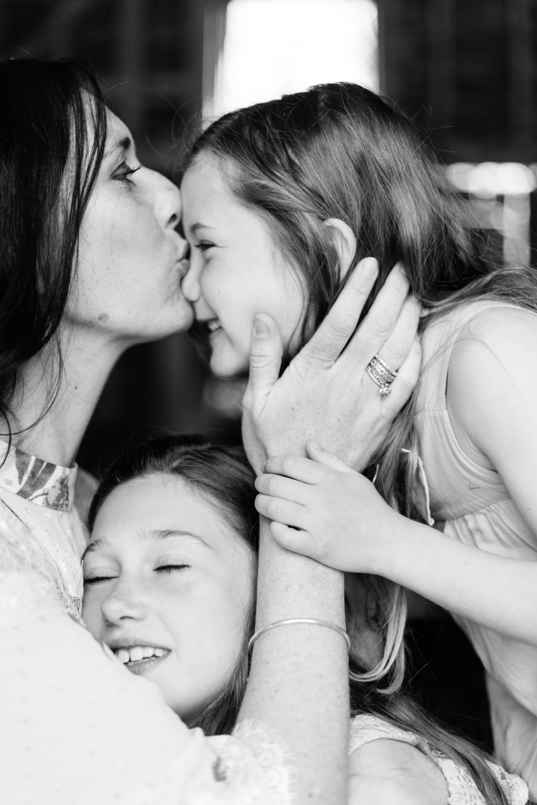 portrait of motherhood by Kika Mitchell photography Chelmsford photographer of mother kissing daughter's nose as she nuzzles other daughter in her arms