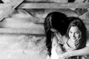 black and white image of mother and daughter by gate, girl looks to camera and mum looks down by Chelmsford photographer Kika mitchell photography