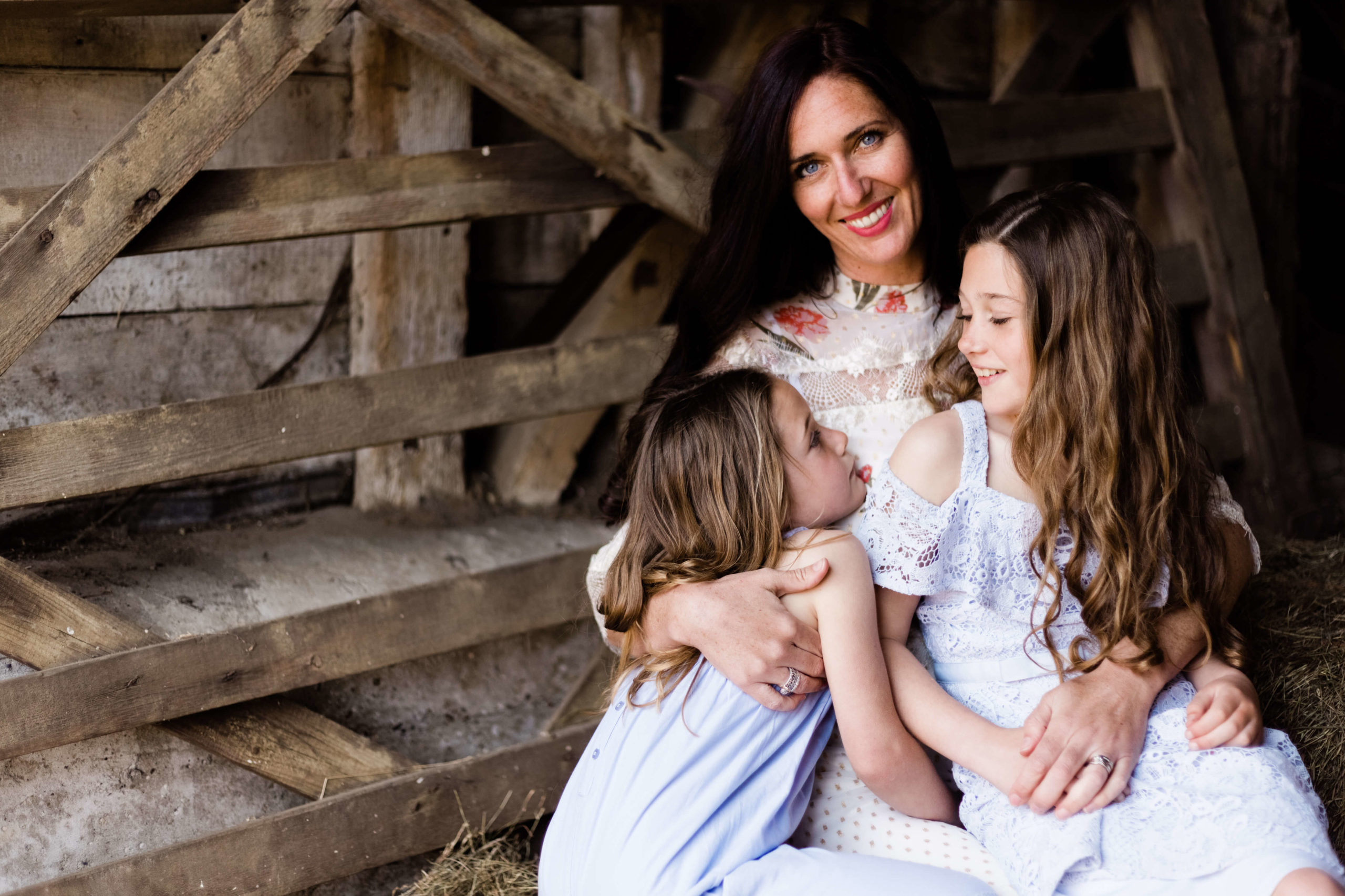 portrait of motherhood by Kika Mitchell Photography, mother holds her daughters and looks to camera