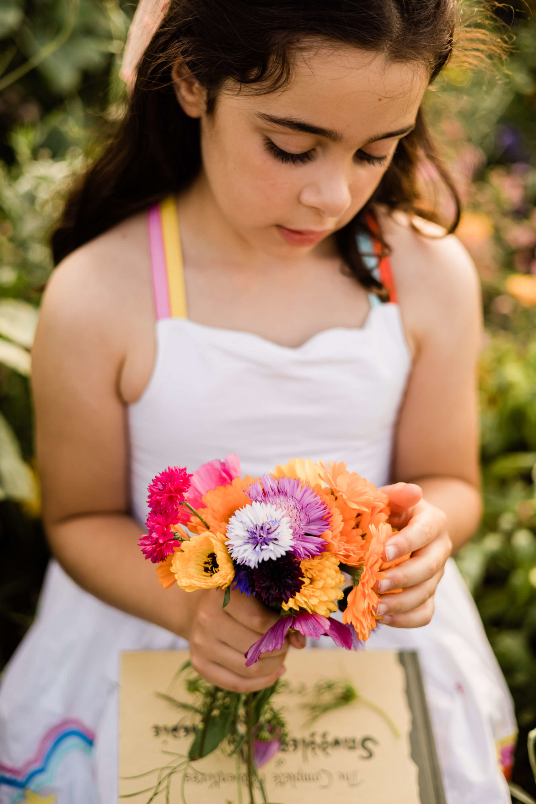 little girl holding flowers and book on lap captured by chelmsford photographer kika mitchell photography