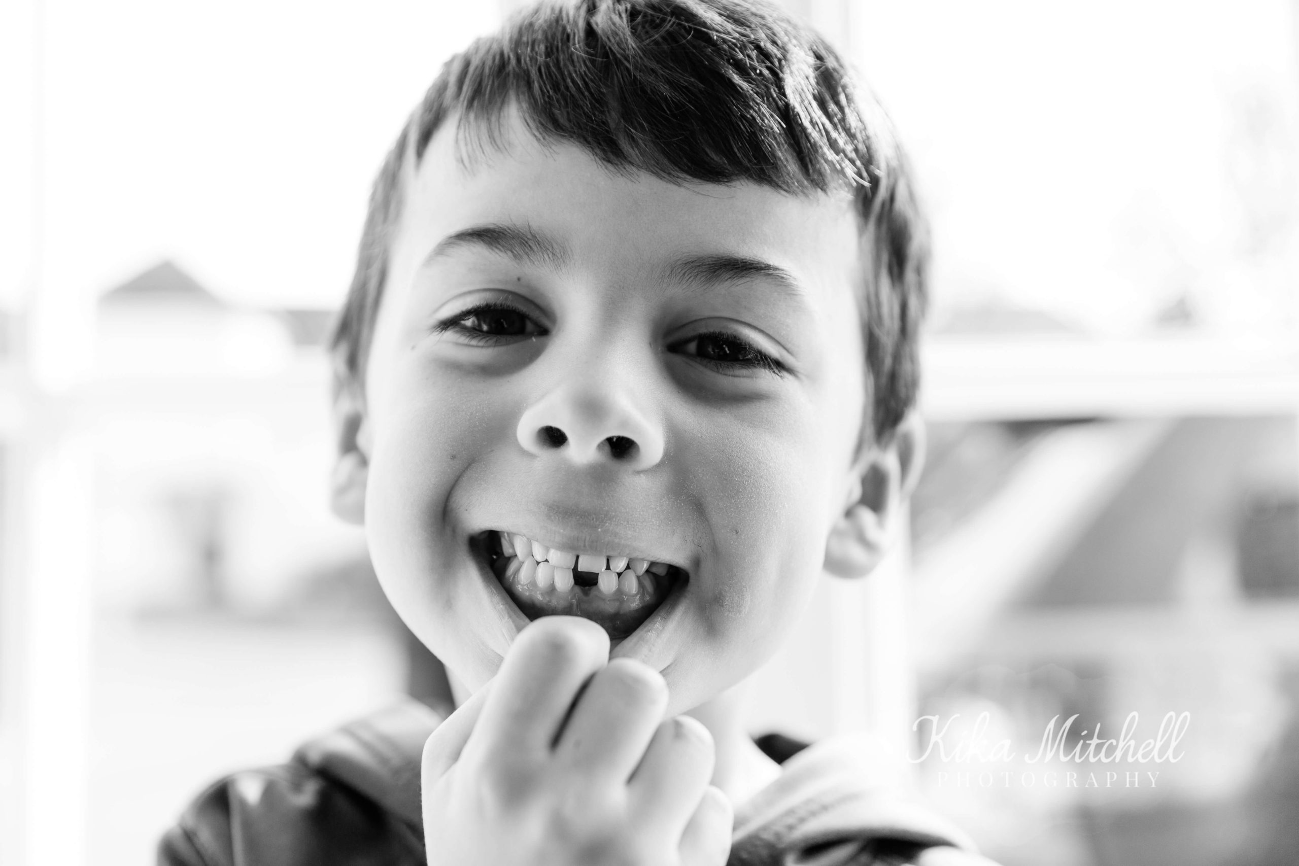 toothless boy smiling showing off the tooth gap in his mouth - black and white photography style shoot